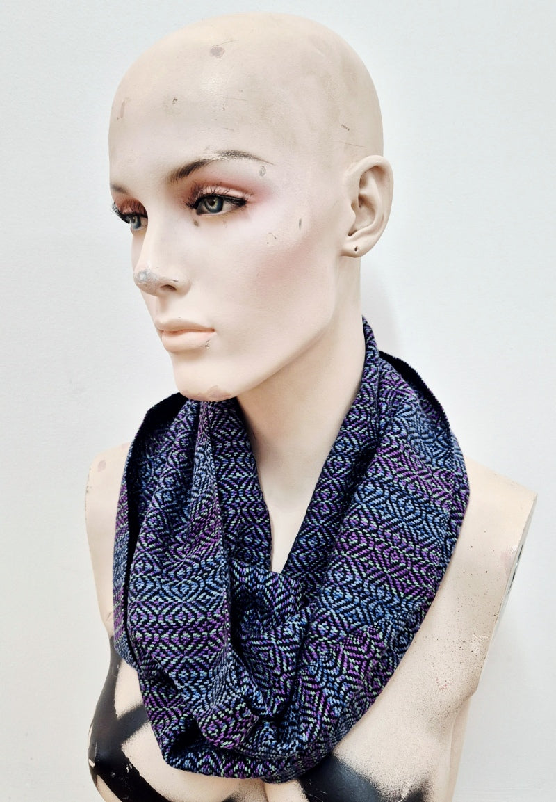 handwoven infinity scarf in purples, blues, greens and black cotton, worn by a creepy mannequin