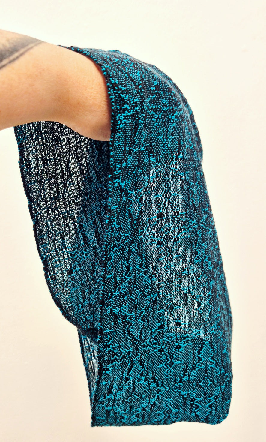 Turquoise blue textured fabric held by a person against a white background