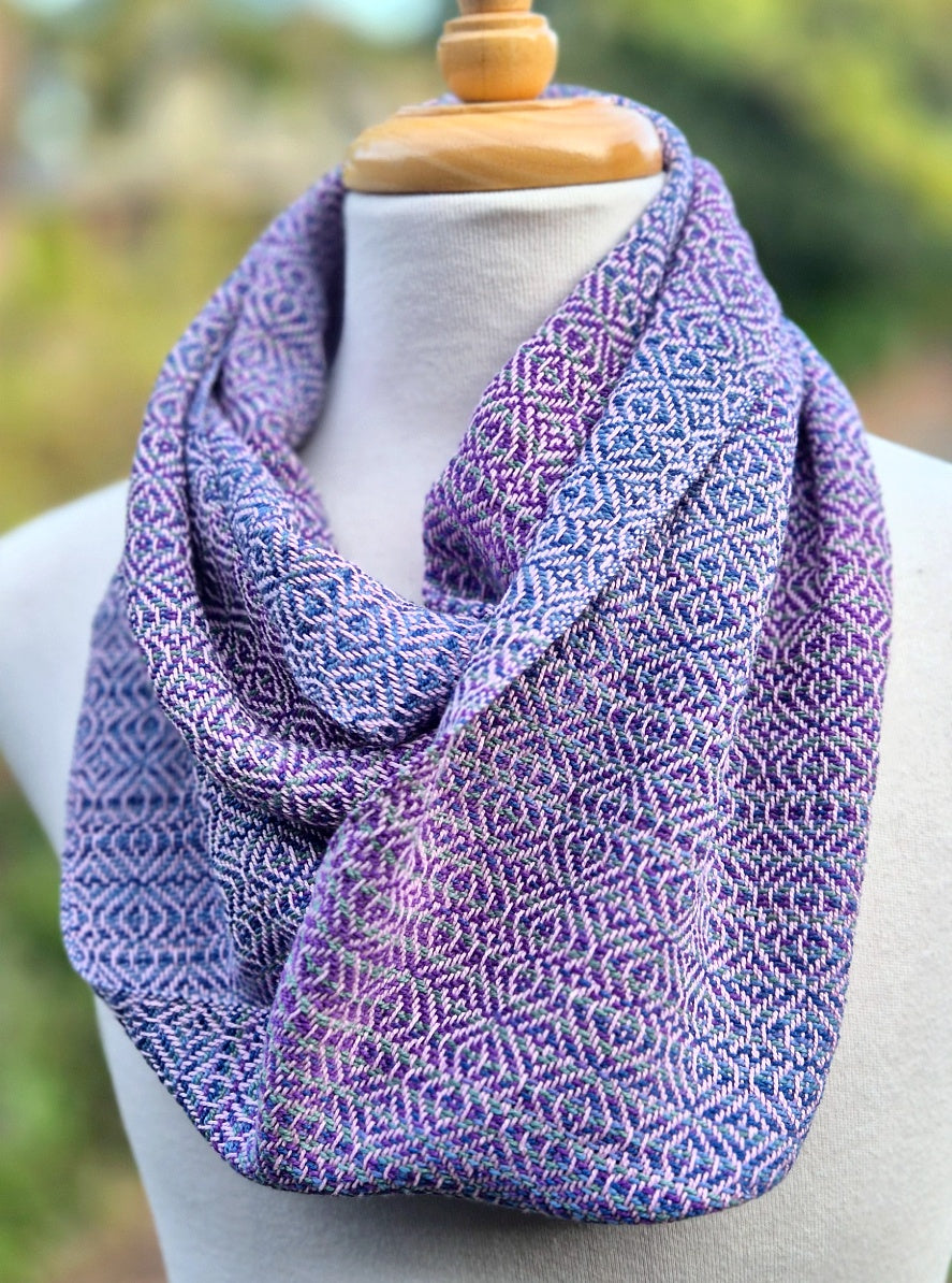 handwoven infinity scarf on a mannequin in shades of purple, light pink and blue