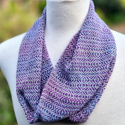 Purple, pink and blue patterned scarf on a mannequin against a blurred natural background