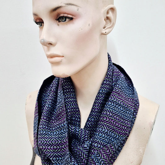handwoven infinity scarf in purples, blues, greens and black cotton, worn by a creepy mannequin