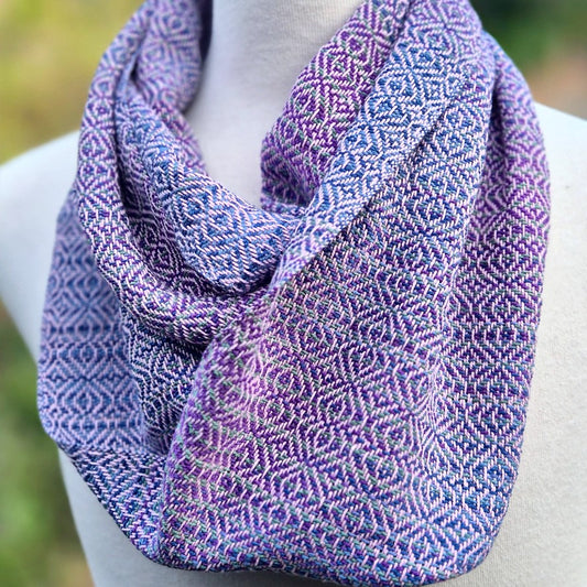 handwoven infinity scarf on a mannequin in shades of purple, light pink and blue