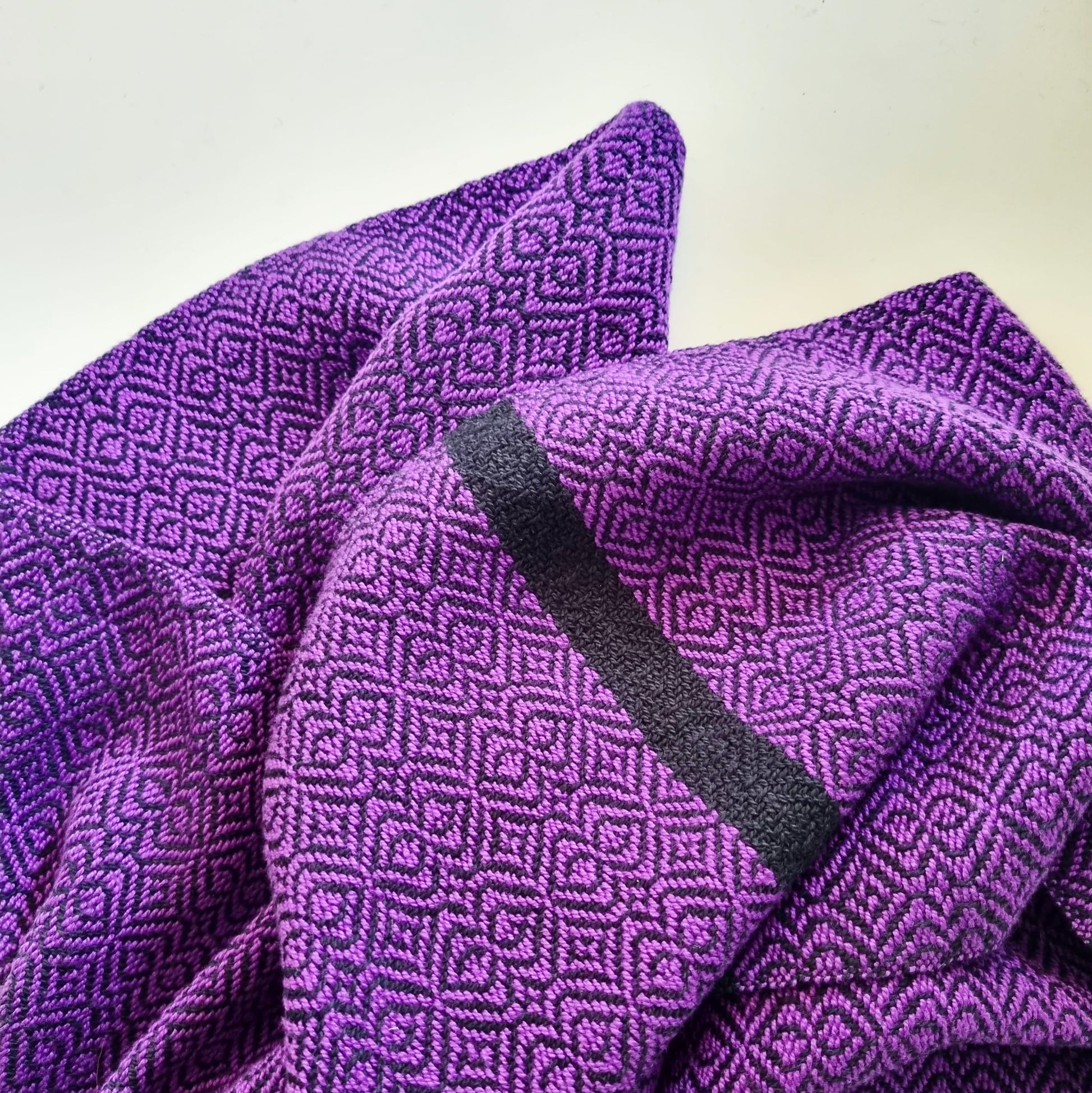 Purple textured handwoven fabric with geometric pattern on a white background